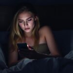 Woman looking sadly at her phone waiting for a text message, demonstrating how to make him obsessed with you starts with understanding mixed signals